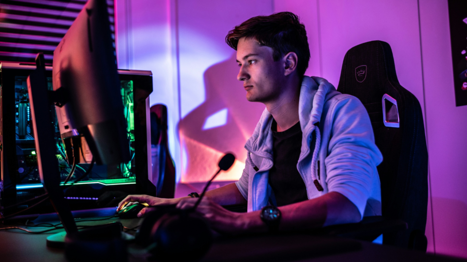 Young male gamer sitting at computer desk