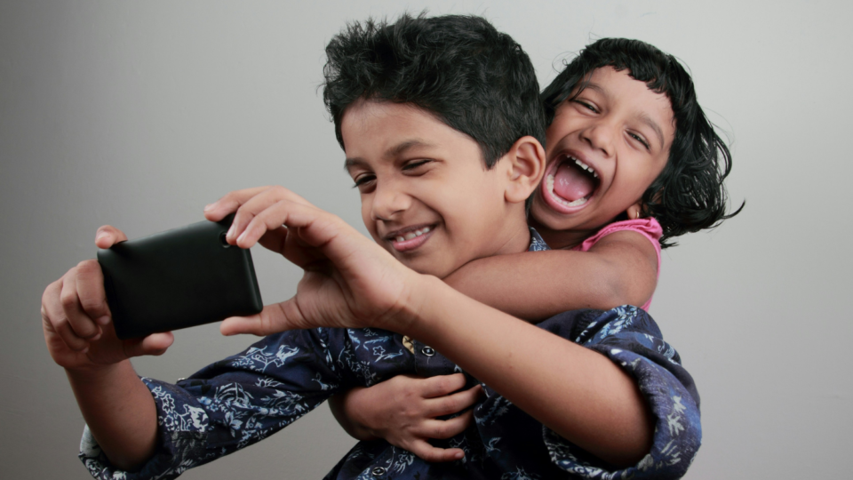 Two young kids playing with phone